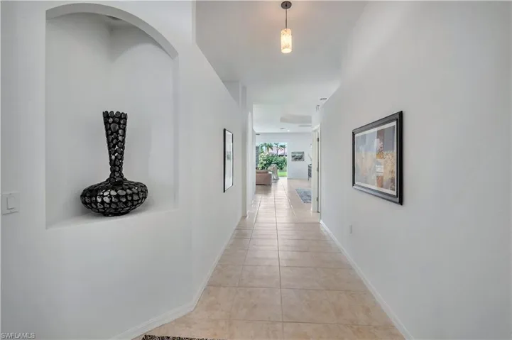 Hallway featuring light tile patterned flooring and baseboards