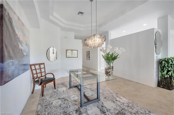 Office space with a raised ceiling, light tile patterned floors, and a chandelier