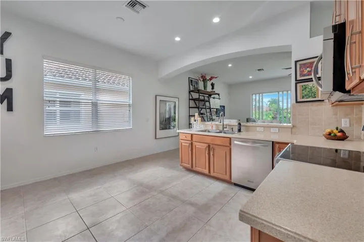 Kitchen featuring recessed lighting, appliances with stainless steel finishes, brown cabinetry, light tile patterned floors, and a peninsula
