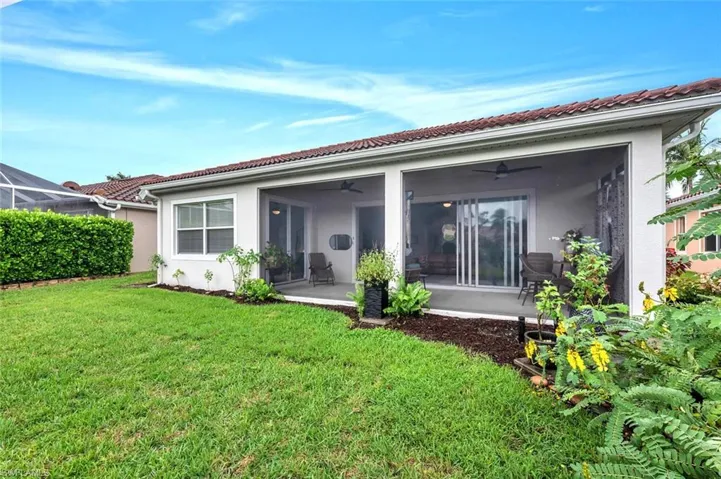 Back of house with a ceiling fan, stucco siding, a yard, a sunroom, and a tiled roof