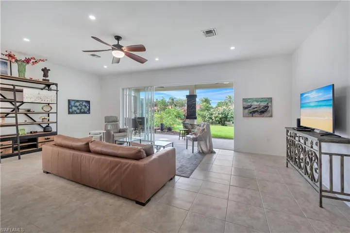 Living room with ceiling fan, light tile patterned flooring, and recessed lighting