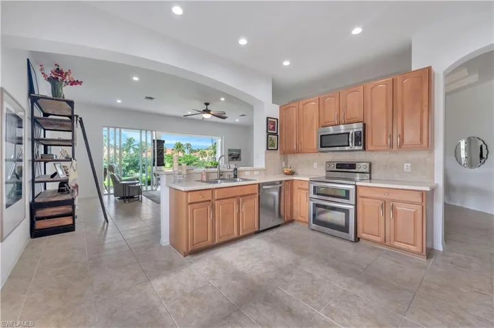 Kitchen featuring stainless steel appliances, light countertops, arched walkways, a ceiling fan, and tasteful backsplash