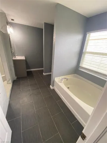 Bathroom featuring tile patterned flooring, vanity, and a bathtub