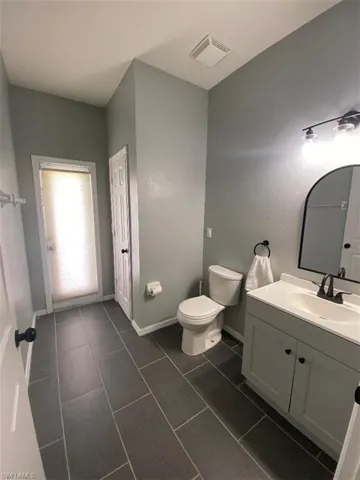 Bathroom with vanity, toilet, and tile patterned floors