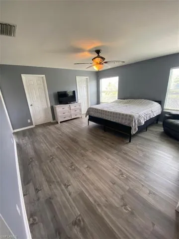 Unfurnished bedroom with multiple windows, hardwood / wood-style floors, and ceiling fan