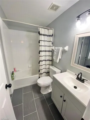 Full bathroom featuring shower / bathtub combination with curtain, vanity, tile patterned floors, and toilet