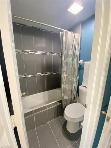 Bathroom with tile patterned floors, toilet, and shower / bath combo