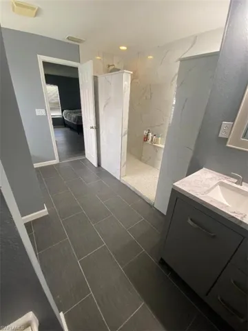 Bathroom featuring vanity, tile patterned floors, and a tile shower