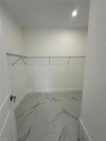 Walk in closet featuring light marble finish flooring