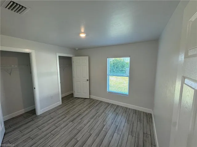 Unfurnished bedroom featuring multiple closets and light wood-type flooring