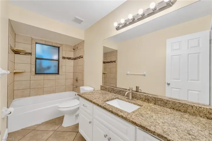Bathroom with vanity, washtub / shower combination, and light tile patterned floors