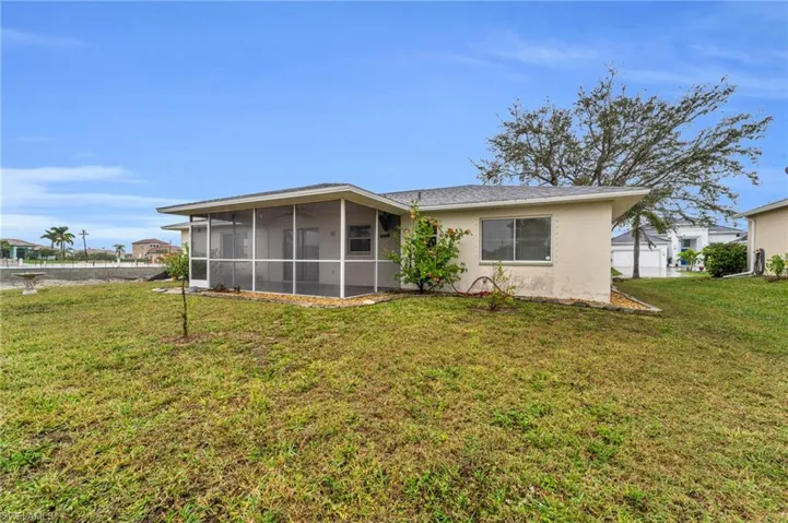 Rear view of house featuring a yard, a sunroom, and stucco siding