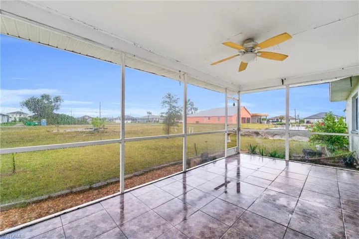 Unfurnished sunroom featuring a ceiling fan and a residential view