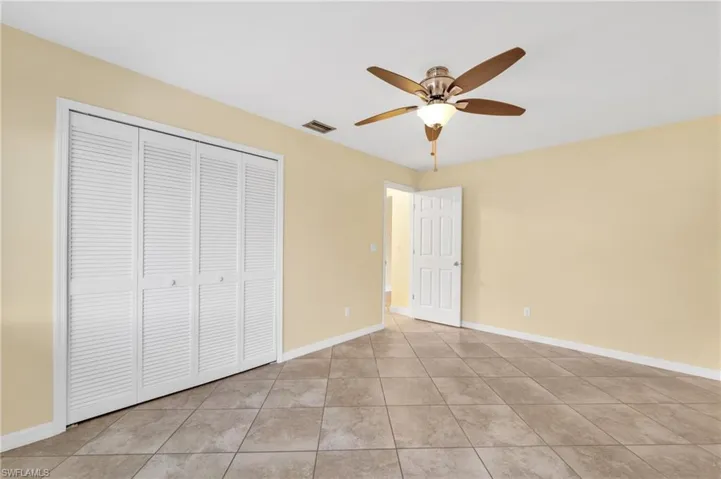 Unfurnished bedroom featuring ceiling fan, a closet, and light tile patterned flooring