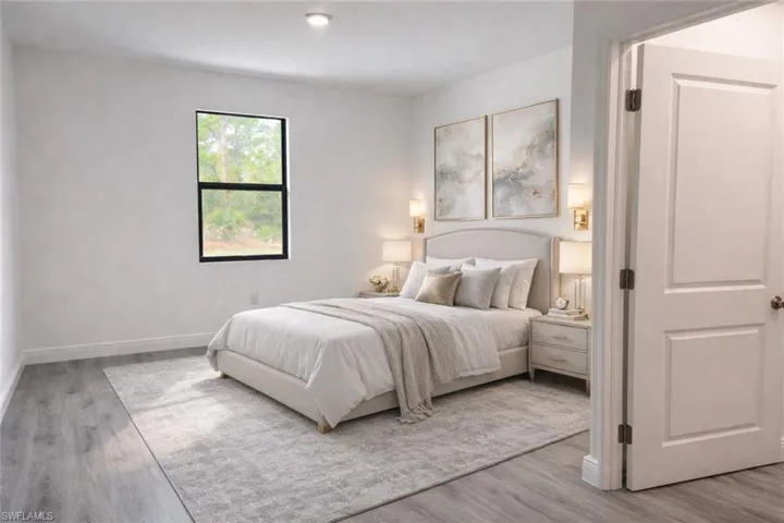 Light-filled sleeping area featuring wood-finish flooring, a contemporary window, recessed lighting, a paneled interior door, and a neutral color palette