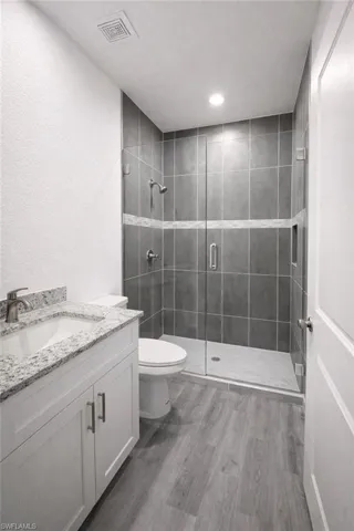 Contemporary bathroom featuring a glass-enclosed shower with gray tile, a decorative accent tile band, and a built-in shower niche