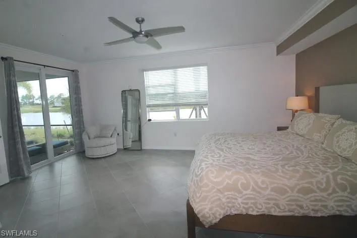 Bedroom with a water view, ceiling fan, multiple windows, and access to outside lanai