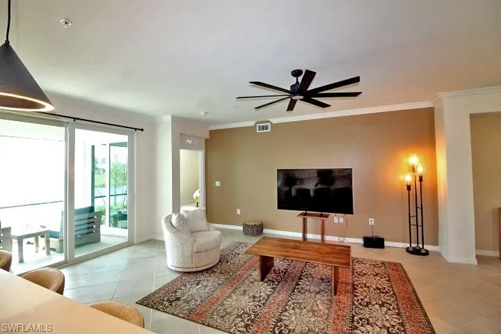Living room with crown molding, light tile floors, and ceiling fan