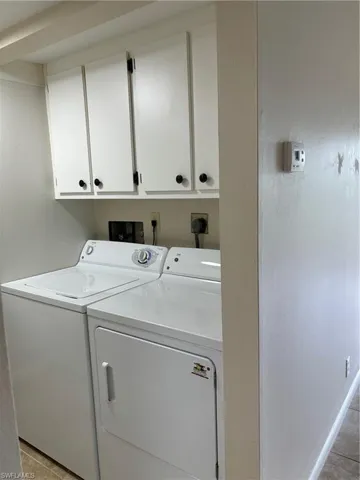 Clothes washing area featuring cabinets, independent washer and dryer, and light tile patterned floors