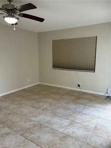 Unfurnished room with ceiling fan and light tile patterned flooring