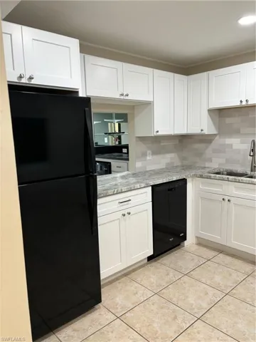 Kitchen with backsplash, fridge, dishwashing machine, and sink