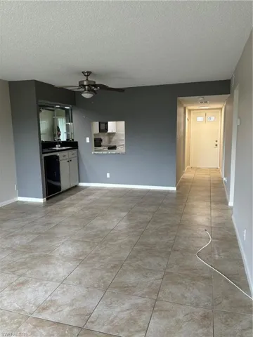 Unfurnished living room featuring a textured ceiling, ceiling fan, light tile patterned floors, and sink