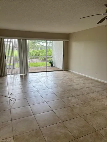 Tiled empty room featuring a textured ceiling and ceiling fan