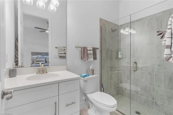 Bathroom with vanity, ceiling fan, toilet, and an enclosed shower
