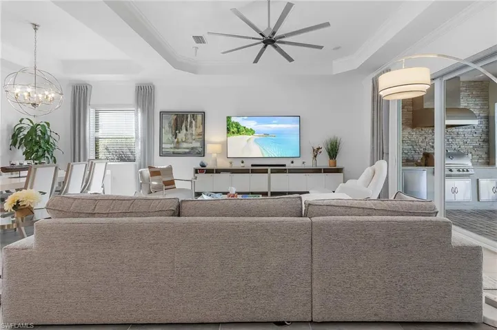 Living room with crown molding, a raised ceiling, and ceiling fan