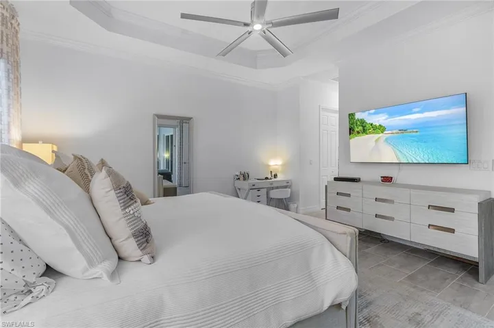 Tiled bedroom featuring crown molding, a raised ceiling, and ceiling fan