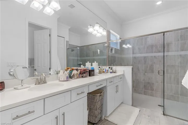 Bathroom featuring vanity, ornamental molding, and a shower with door