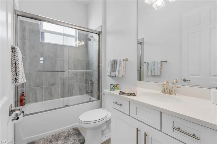Full bathroom featuring vanity, toilet, and shower / bath combination with glass door