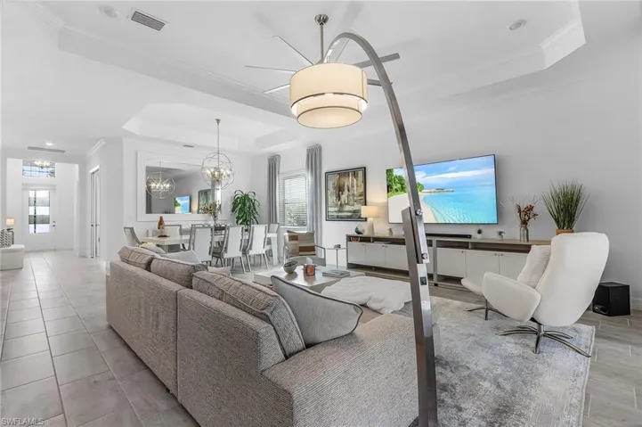 Living room featuring crown molding, ceiling fan, and a raised ceiling