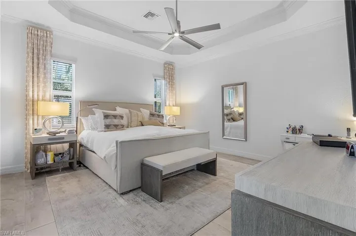 Bedroom with ceiling fan, a raised ceiling, ornamental molding, and light hardwood / wood-style floors