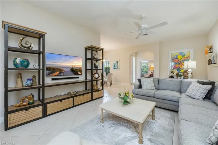 Living area with arched walkways, light tile patterned floors, and ceiling fan