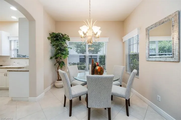 Dining room with light tile patterned floors, arched walkways, and a chandelier