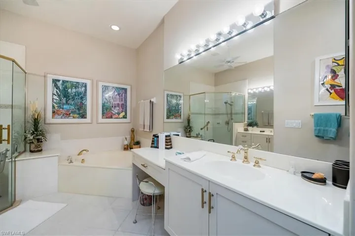 Full bath with ceiling fan, a garden tub, a shower stall, two vanities, and light tile patterned floors