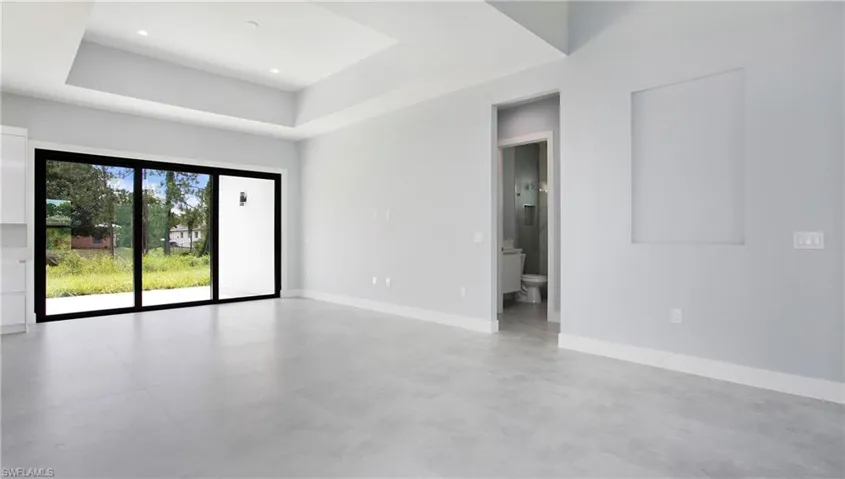 Unfurnished room featuring a raised ceiling and concrete floors