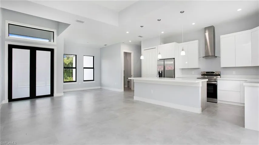 Kitchen featuring appliances with stainless steel finishes, wall chimney exhaust hood, modern cabinets, light countertops, and decorative light fixtures