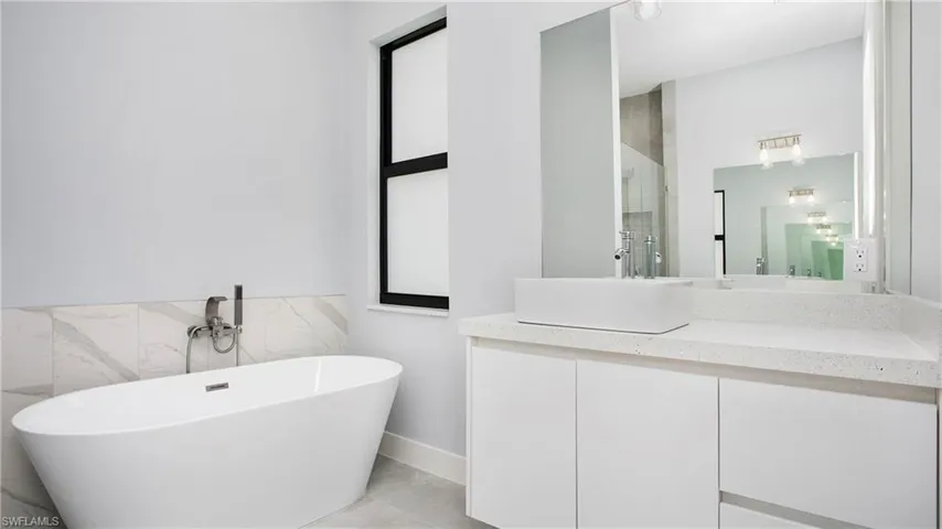 Full bath with a freestanding tub, vanity, tile walls, and a shower