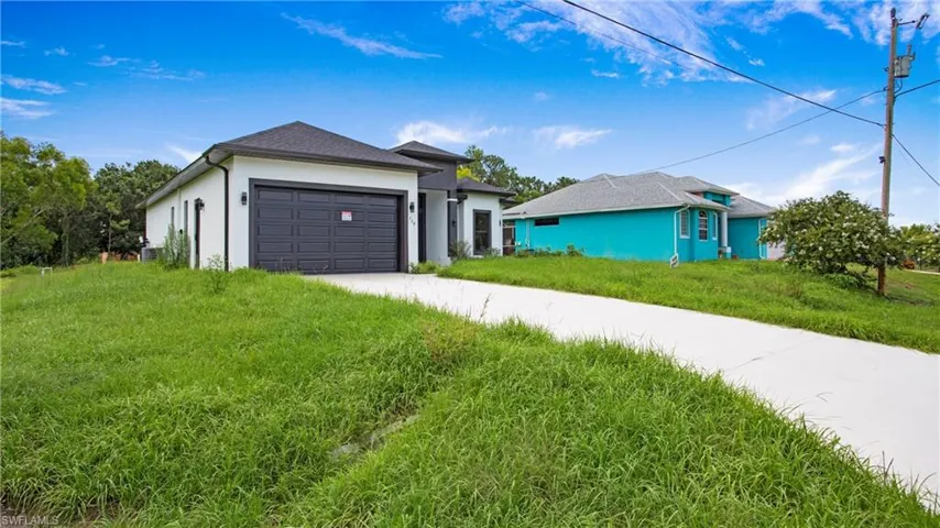 Ranch-style home with driveway, an attached garage, stucco siding, and a front lawn