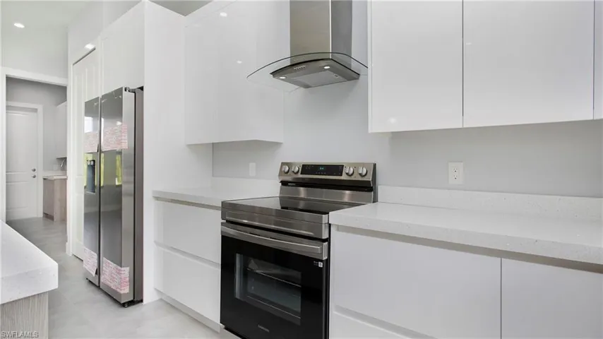 Kitchen with dishwasher, modern cabinets, light brown cabinets, light countertops, and an island with sink