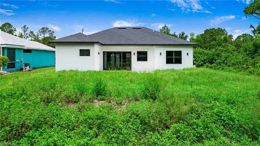 Back of house featuring stucco siding and roof with shingles