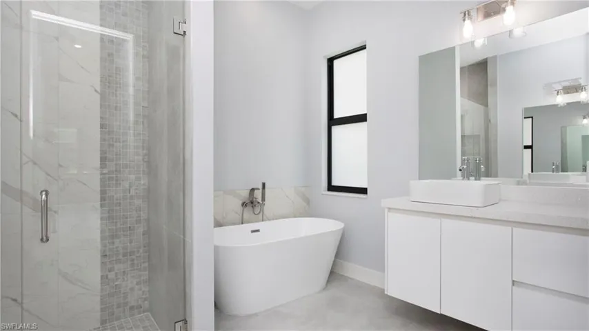 Full bathroom with a shower stall, vanity, and a freestanding tub