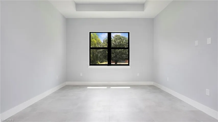 Spare room with a tray ceiling and baseboards