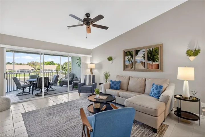 Living room featuring ceiling fan, vaulted ceiling, light tile patterned flooring, and a residential view