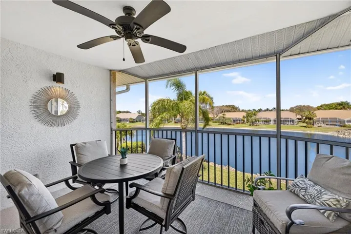 Sunroom / solarium featuring a ceiling fan, outdoor dining space, and a water view