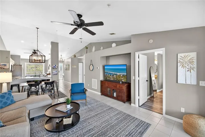 Living area with ceiling fan, light tile patterned floors, and a high ceiling