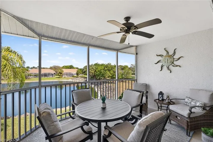 Sunroom with outdoor dining space, a ceiling fan, a water view, and a balcony