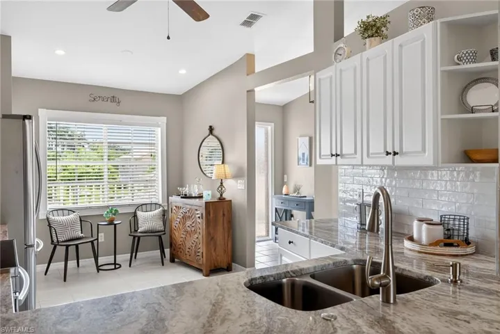 Kitchen with open shelves, stainless steel appliances, white cabinets, light tile patterned flooring, and light stone counters